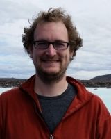 a photo of Nick Bolten, a man with glasses standing outdoors.