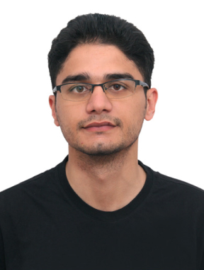 A man in a black t-shirt and spectacles stands tall in front of the imposing brick building at the University of Washington Seattle campus, his focused gaze and confident stance capturing the essence of the bustling academic atmosphere surrounding him.