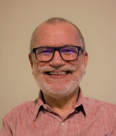 Man wearing glasses smiles at camera. 